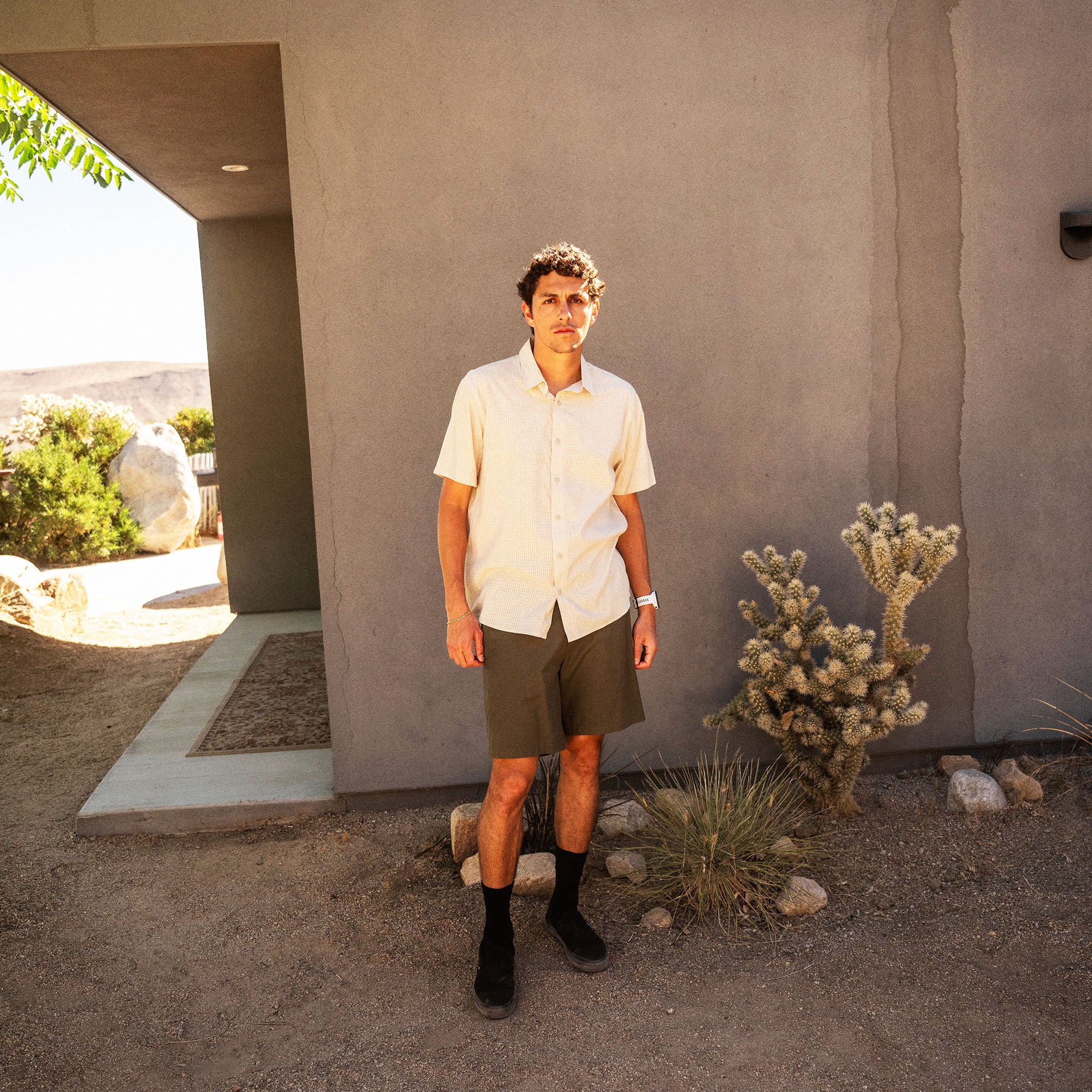 Bless Up Breathable Stretch Shirt in Sand, worn by a model with olive shorts in a desert courtyard