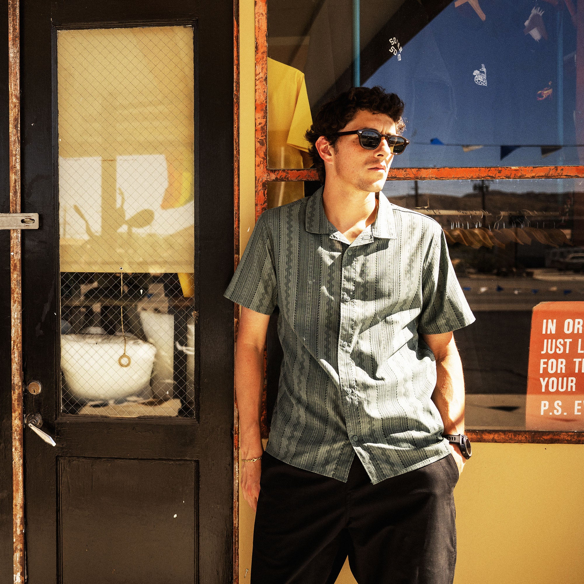 Bless Up Trail Button Up Shirt in Dark Slate, worn by a model against a weathered wall