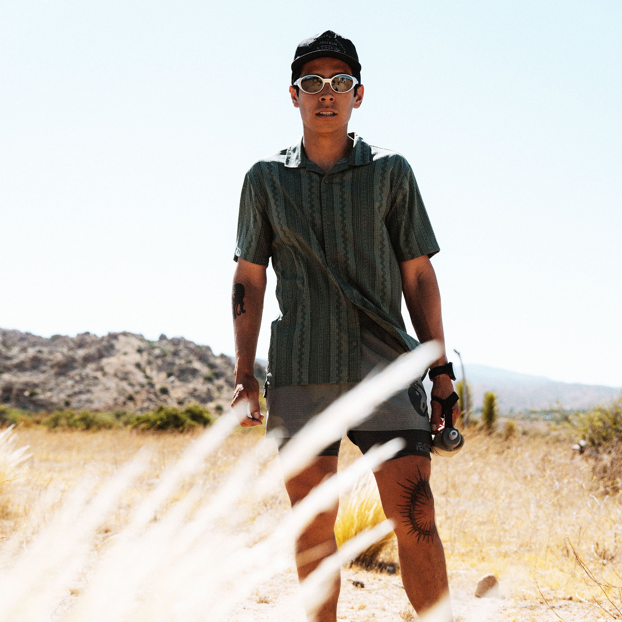 Bless Up Trail Button Up Shirt in Ebony, worn by a model holding a skateboard in a desert landscape