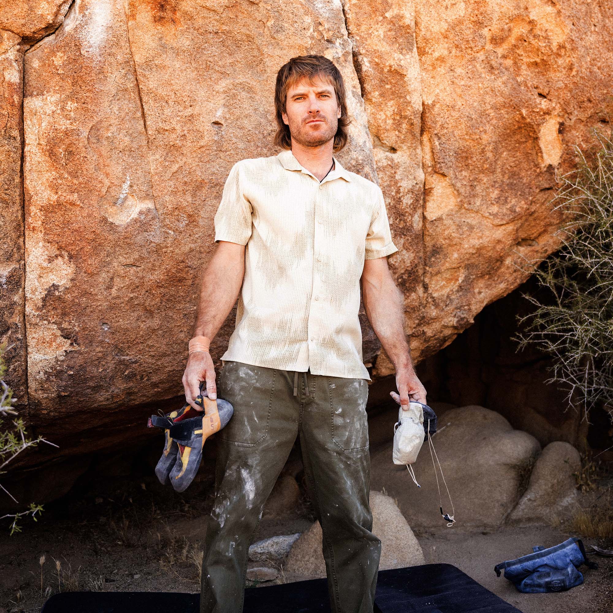 Bless Up Trail Button Up Shirt in Sand, worn by a climber carrying gear