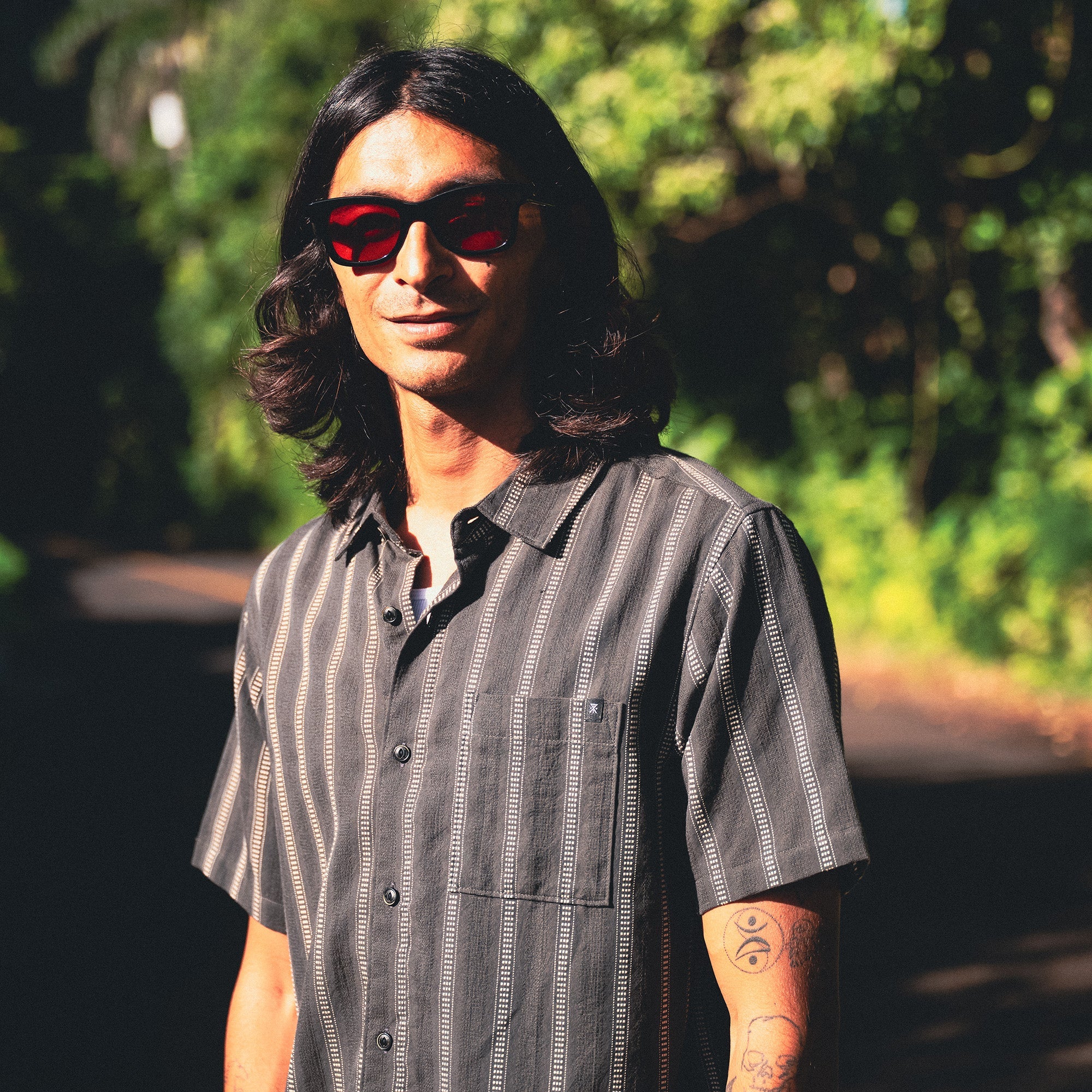 Stylish adventurer wearing sunglasses pairing with the Crosswinds Button Up Shirt, perfect for outdoor travel and exploration.