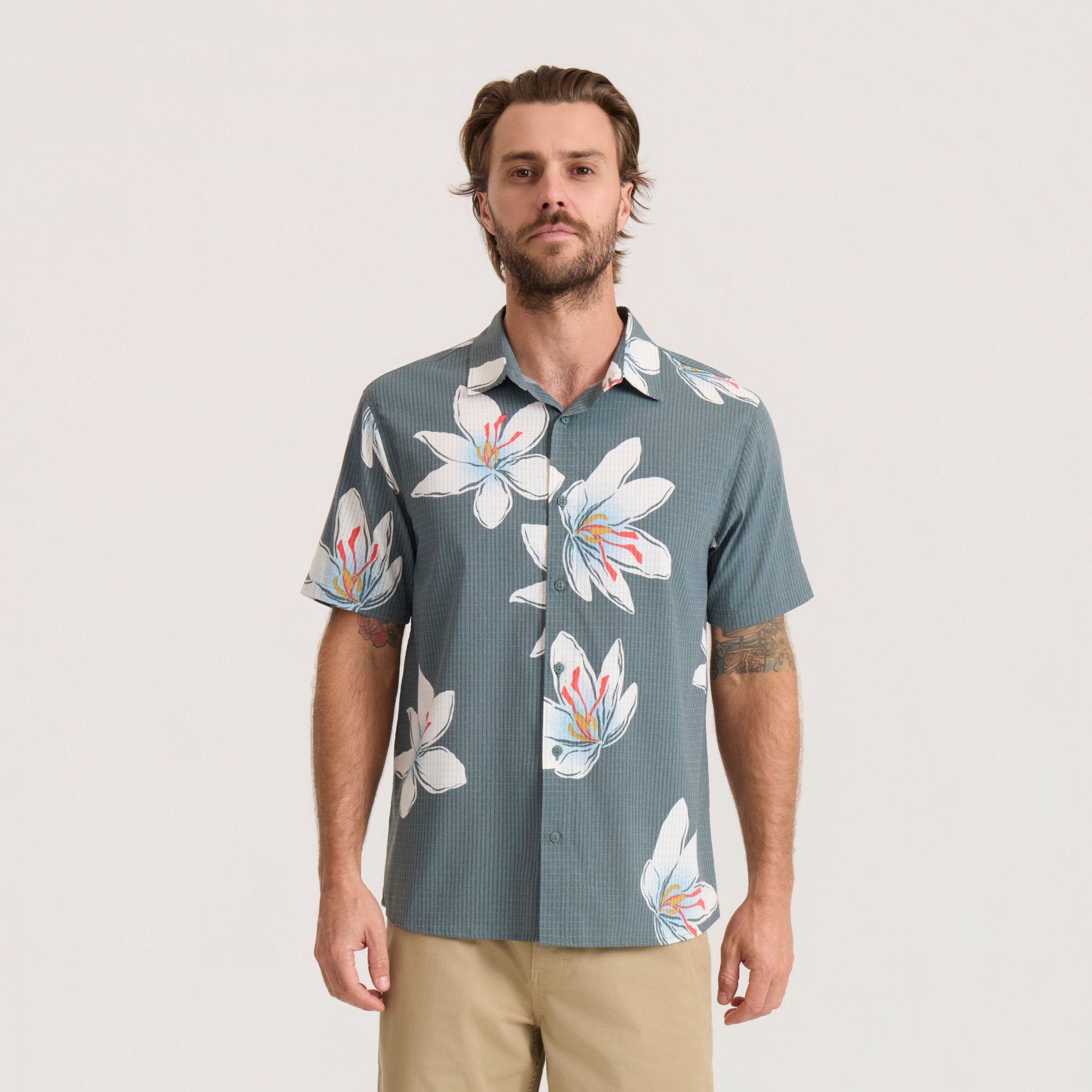 Slate green short-sleeve floral shirt with white and orange flowers worn by man with tan pants, front view